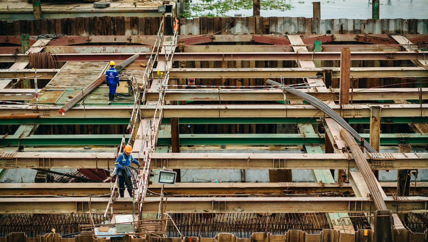 A group of construction workers working on a building site rooftop, surrounded by scaffolding and tools